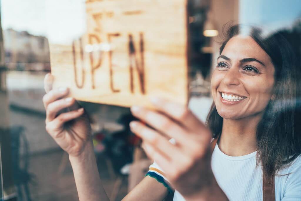 cafe owner turning shop sign to open