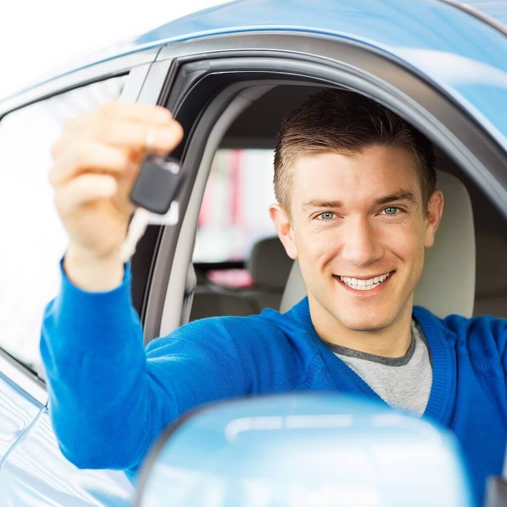 Man in car holding up car keys