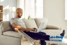 man in moon boot working on laptop at home